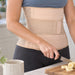 En person med ryg- og lændestøtte fra Kroppsbutiken skærer en banan i køkkenet.
