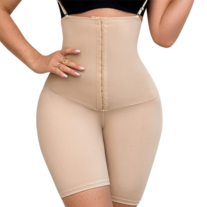 En kvinde iført beige figurformende shorts med skulderstropper, høj talje og knaplukning, der går fra skuldrene til lårene.