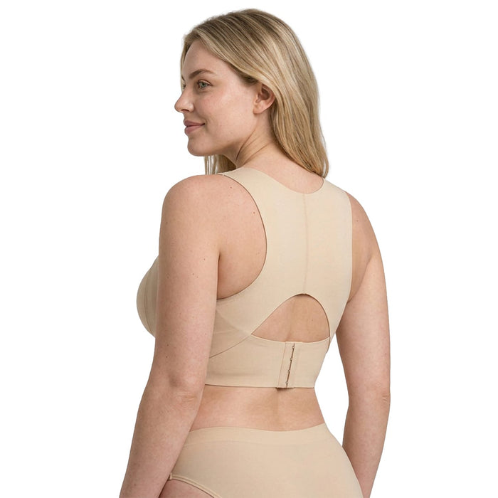 En kvinde i butikken iført en beige Trueform Shaping-bh, set bagfra med nøglehulsudskæring og hægtelukning.