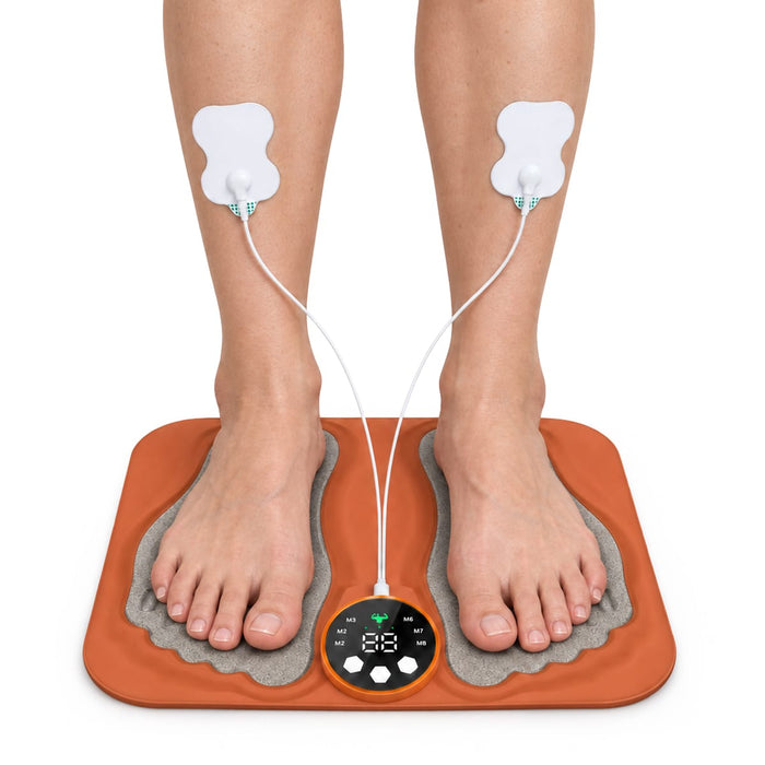 Brugeren anvender Kroppsbutiken SE TENS-fodmassagemåtte med elektroder på læggene til muskelstimulering.