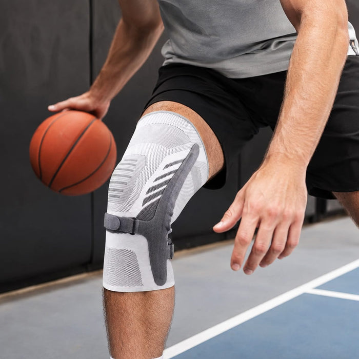 En person med et sportsbind med spænde fra Kroppsbutiken dribler en basketbold indendørs med højre hånd.