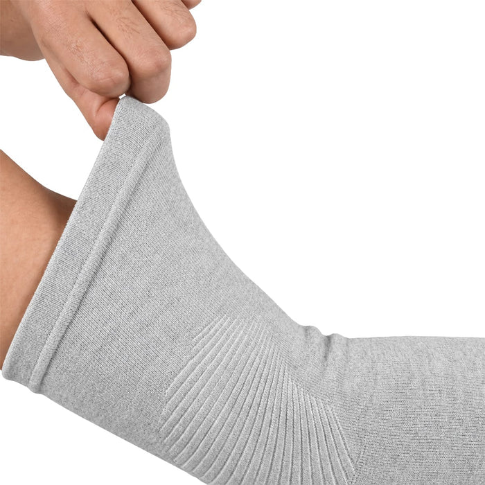 En hånd trækker en grå, ribbet albuebandage af bambus op på en bøjet arm foran en hvid baggrund.